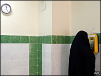 Một phụ nữ che mạng kín mặt đang sử dụng điện thọai trả tiền trước trong nhà tù