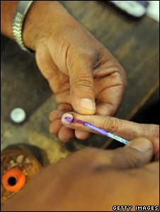 An Indian election officer marks the finger of a voter with ink during the first phase of polling in Varanasi on 16 April