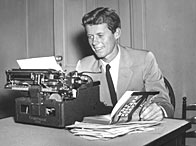 Future American president John F Kennedy, sits at a typewriter, holding open his published thesis, 'Why England Slept' (c. 1940)