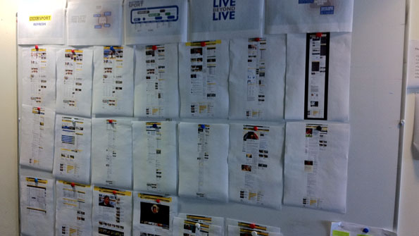 Picture of printouts of site designs, on a whiteboard, on a wall.