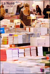 Funcionária arruma estande com livros no Salão de Paris
