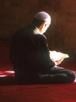 Boy wearing prayer cap and reading the Qur'an