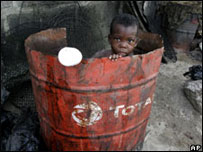 A child plays in an empty oil drum