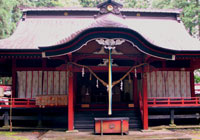Red-painted shrine at Yatsuki Tsutsukowake decorated with paper streamers and rainbow ribbons