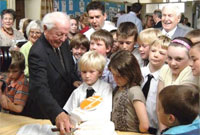 Y Parch Huw Ethall yn torri'r gacen i ddathlu