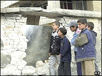 Jovens observam parede destruída em operação de forças americanas em Cabul