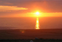 Yr haul yn machlud dros y mor, gyda mynyddoedd Wicklow, Iwerddon ar y gorwel