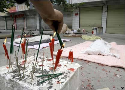 Thân nhân các nạn nhân thắp nến ở gần đống đổ nát của một toà nhà bị sập.