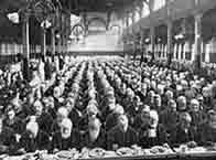 Newspaper picture showing a packed hall of workhouse staff sitting down to dinner