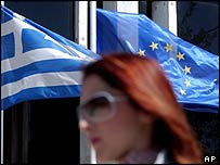 Atéňanka míjí vlajky Řecka a EU