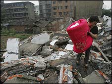 Một phụ nữ bê chăn chiếu qua một đống đổ nát ở Tứ Xuyên - ngày 23 tháng 5 năm 2008