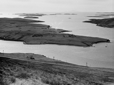 Black and white view looking down at the flat, grassy island of Trondra from the Hill of Easterhoull.