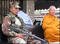 Một người lính Thái Lan bảo vệ nhà sư đang thu hồi vũ khí ở tỉnh Narathiwat
