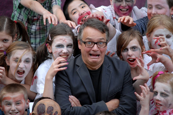 Charlie Higson surrounded by school children dressed as zombies.
