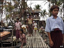 A family stand outside their damaged house in the Irrawaddy Delta on 11 May 2008