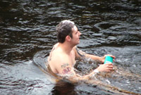 Dyn ym ymolchi yn yr afon