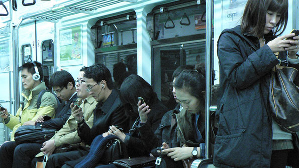 Koreans looking at their phones on the train