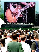 Guitar player on large screen at rock restival
