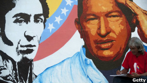 Artista trabalha em frente a painel com imagem de Chávez em Caracas (foto: Getty)