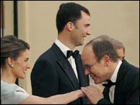 O príncipe Albert de Mônaco beija a mão de Letícia. O príncipe Felipe aparece ao fundo.
