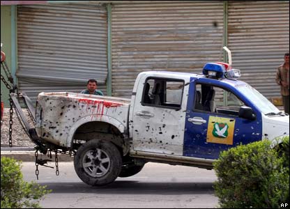 Mobil polisi yang rusak ditarik dari lokasi pemboman dengan mobil derek sipil.