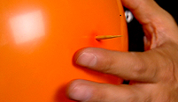 A wooden skewer through a balloon.