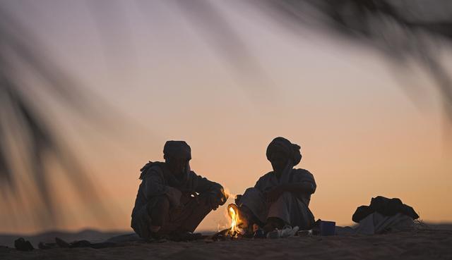 Sillouette of two nomadic people sitting around a camp fire at sunrise (image: Photolibrary.com)