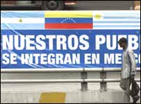 Homem caminha ao lado de propaganda do Mercosul em Caracas, Venezuela