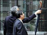 Xem giá cổ phiếu bên ngoài một hãng giao dịch ở Tokyo