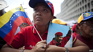 Mulher segura uma foto do presidente Hugo Chávez e a bandeira da Venezuela durante evento em Caracas (AP)