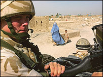 Helmand'da bir NATO askeri ve çocuğuyla yürüyen kadın