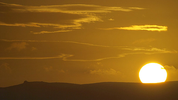 Sun looms large behind mountain horizon