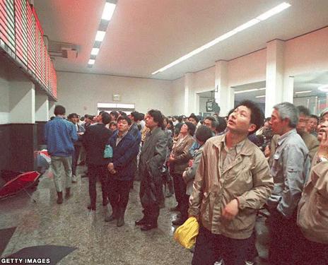 Picture of people looking up at the stock exchange board
