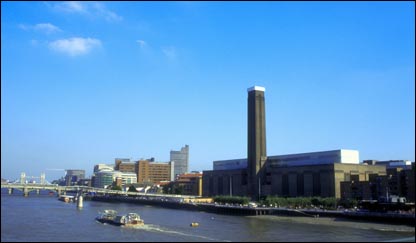 Vista panorâmica da Tate Modern, o museu de arte moderna de Londres, à beira do Tâmisa, com barcos cruzando sob a Ponte do Milênio e com a ponte da Torre de Londres ao fundo. Crédito: www.britainonview.com