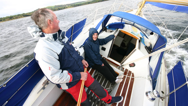 Two people aboard a yacht under sail