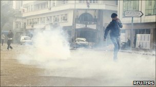 Protesters walk through tear gas during clashes with riot police in downtown of the capital Tunis January 14, 2011. 