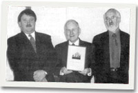 Y Parch Iwan Llewelyn Jones yn cyflwyno'r englyn i T. Elwyn Griffiths gyda'i gyd-ddiacon o awdur Twm Prys-Jones