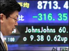 Một người đi qua bảng giá chứng khoán ở Tokyo