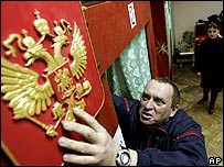 پولنگ سٹیشن کے باہر ایک شخص روس کا ایمبلم لگا رہا ہے