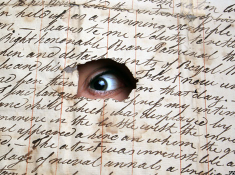 A eye looks through a hole in an old letter