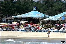 Man walks past sunbeds on beach in Goa
