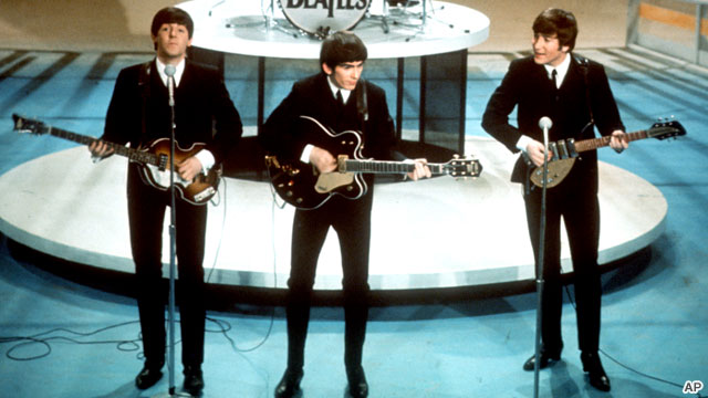 Paul McCartney, George Harrison e John Lennon, com Ringo Starr ao fundo.