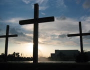 A row of three darkened crosses at sunrise