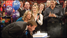 A man blowing out candles on a cake at a party