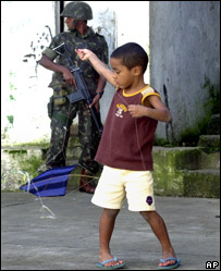 Menino brinca diante de soldado que patrulha favela carioca
