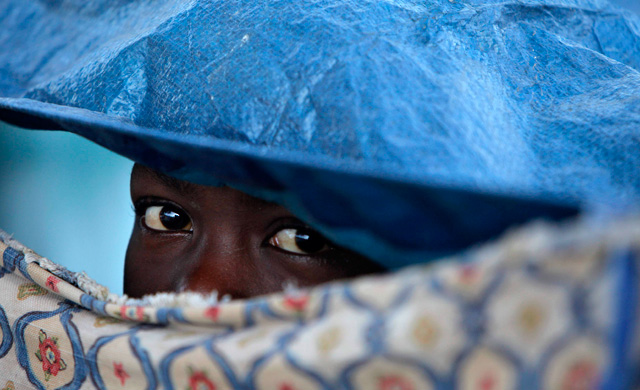 A child peers through a gap in a fabric shelter. (Photo: AP)