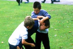 Three boys fight in a playground