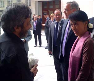 Hamid holding a kebab and speaking to Aung San Suu Kyi