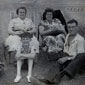 Gerry's Father is seated on the grass with his Mother wearing the floral dress. A young Gerry is seated in the middle