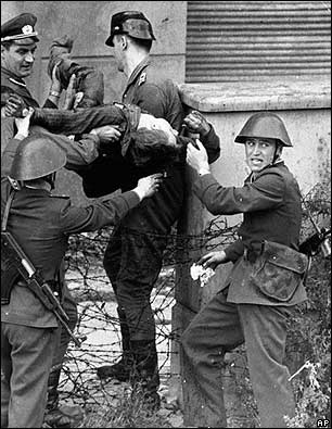 Guardias fronterizos de Berlín Oriental cargan a un ciudadano moribundo que intentó escalar el muro hacia la libertad